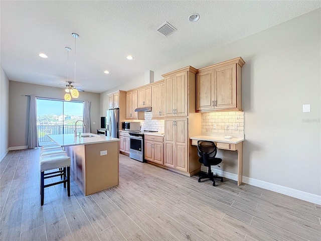 kitchen featuring stainless steel appliances, light hardwood / wood-style flooring, a center island with sink, and a kitchen breakfast bar