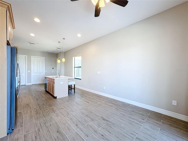 kitchen featuring a center island with sink, sink, light hardwood / wood-style flooring, and hanging light fixtures