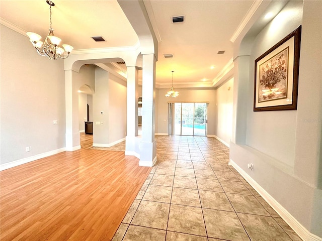 empty room featuring an inviting chandelier, ornamental molding, and light wood-type flooring