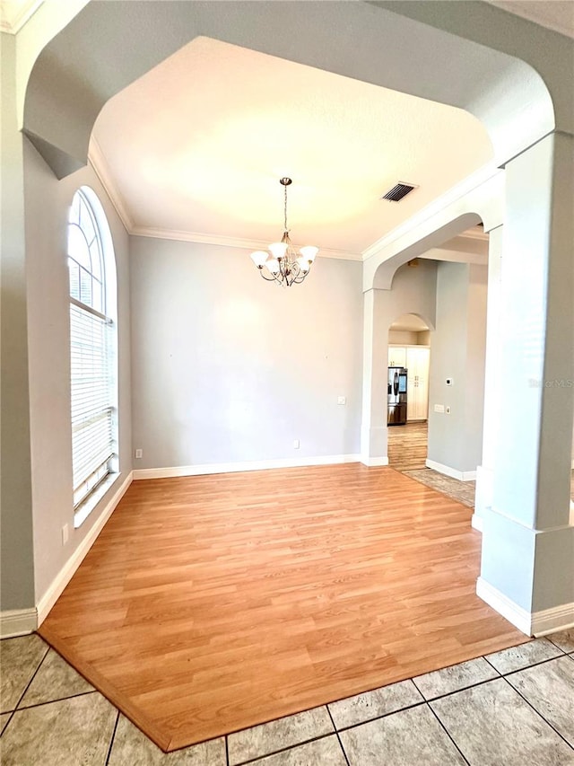 spare room with an inviting chandelier, light wood-type flooring, and crown molding