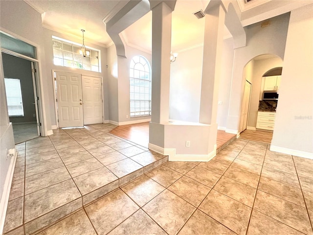 entrance foyer with visible vents, arched walkways, light tile patterned floors, baseboards, and ornamental molding