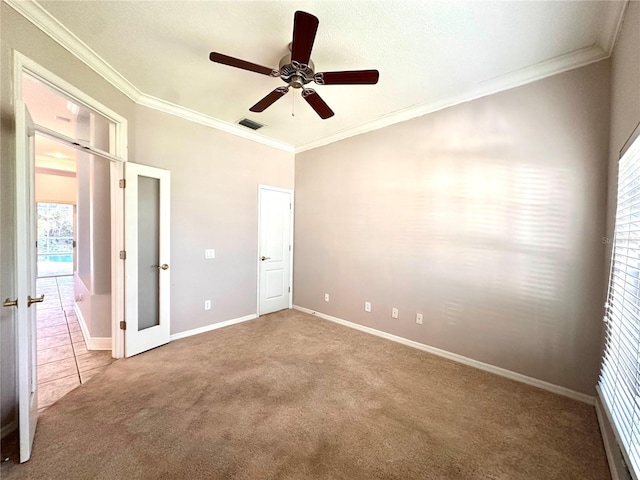 unfurnished bedroom with carpet floors, a ceiling fan, baseboards, visible vents, and ornamental molding