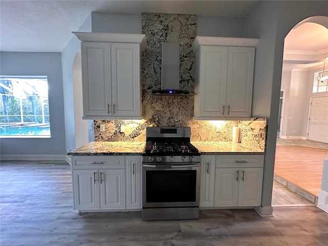 kitchen with plenty of natural light, light hardwood / wood-style flooring, white cabinets, and gas range