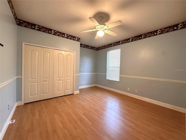 unfurnished bedroom with baseboards, a ceiling fan, light wood finished floors, and a closet