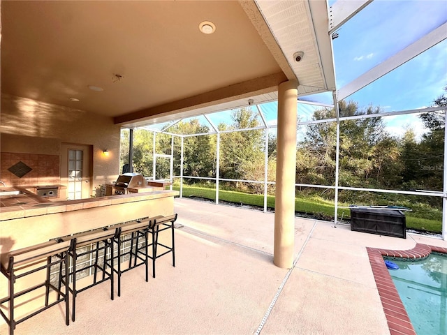 view of patio with a lanai, a grill, and exterior bar