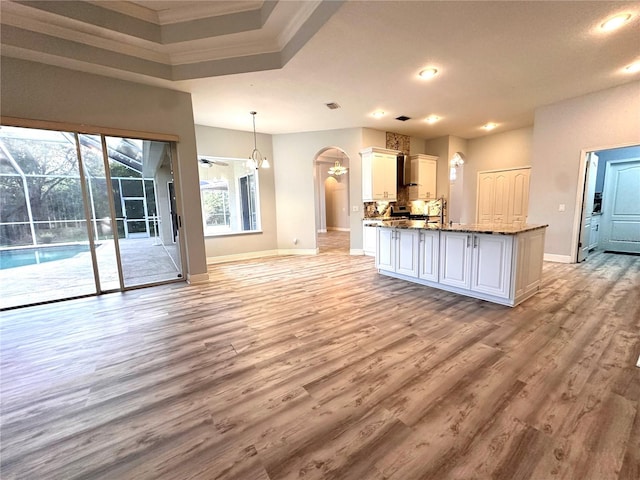 kitchen with stone countertops, light hardwood / wood-style floors, pendant lighting, white cabinets, and ornamental molding