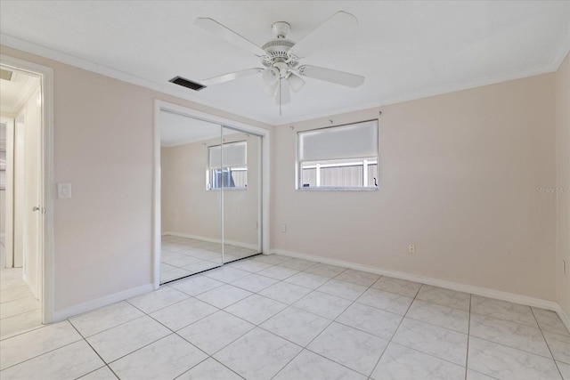 unfurnished bedroom featuring crown molding, light tile patterned flooring, a closet, and ceiling fan