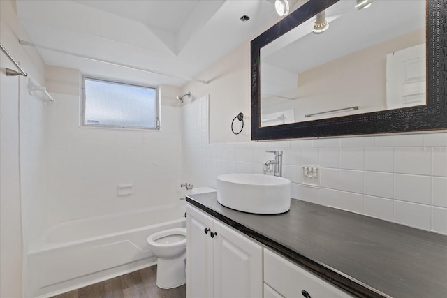 full bathroom featuring wood-type flooring, tile walls, toilet, vanity, and tiled shower / bath combo