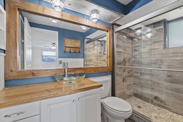 bathroom featuring vanity, a shower with shower door, toilet, and ceiling fan