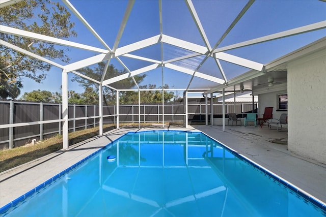 view of swimming pool with a patio area, ceiling fan, and glass enclosure