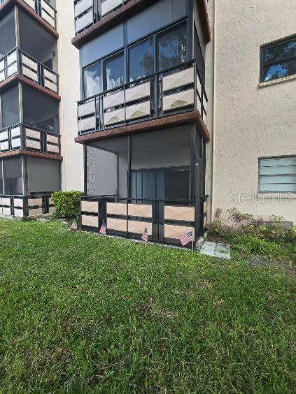 back of house featuring a lawn and a balcony