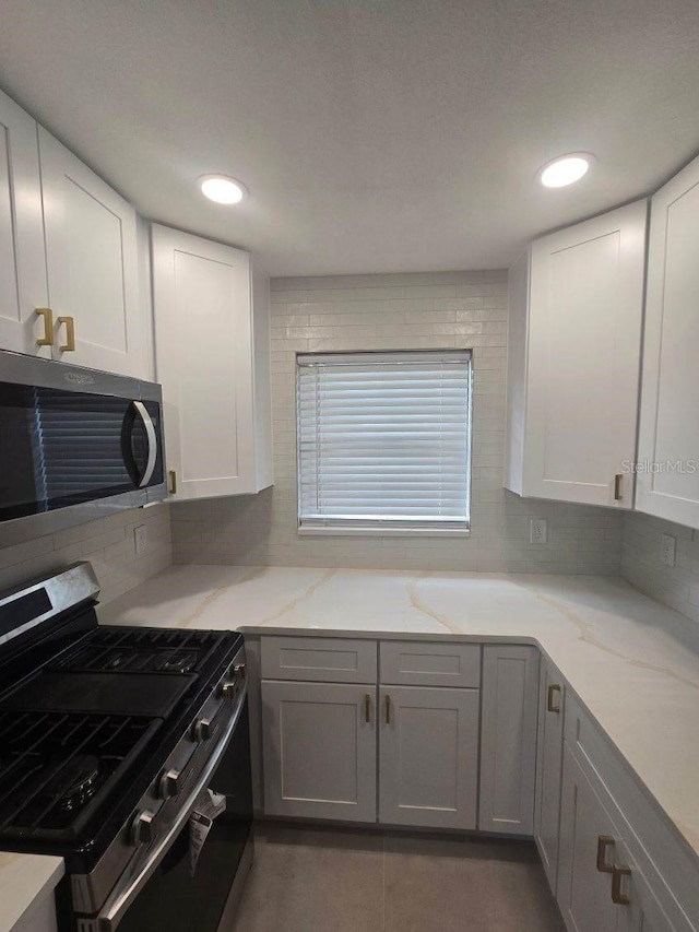 kitchen featuring white cabinetry, light stone counters, stainless steel appliances, and tasteful backsplash