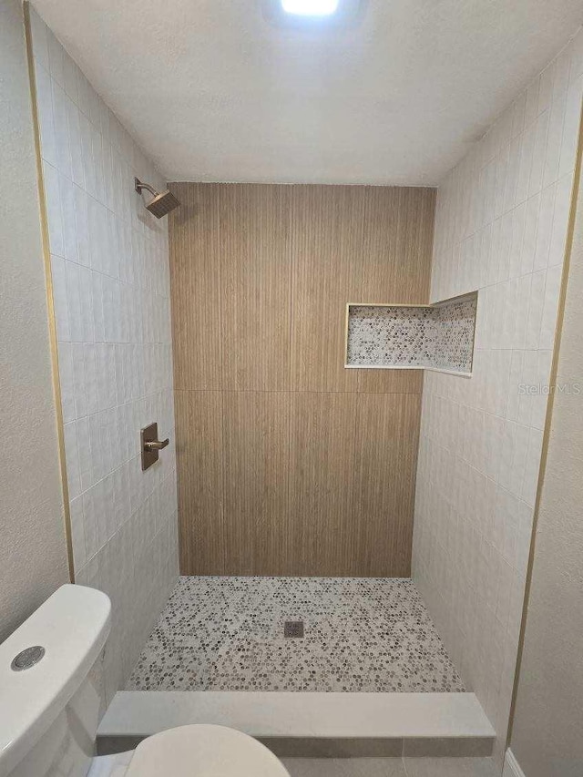 bathroom featuring a tile shower and toilet