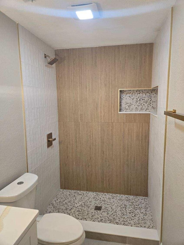 bathroom featuring vanity, toilet, and a tile shower