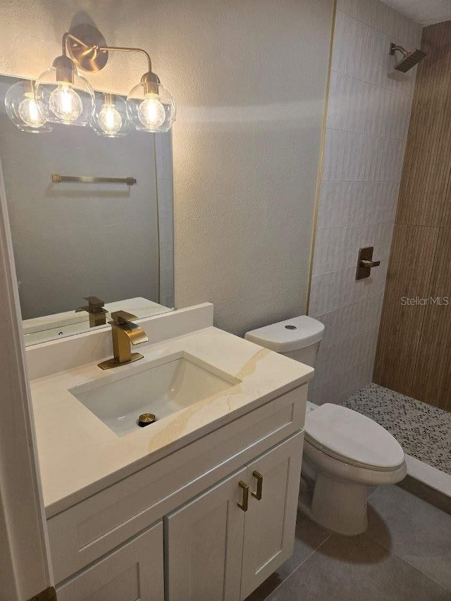 bathroom featuring vanity, tiled shower, toilet, and tile patterned flooring