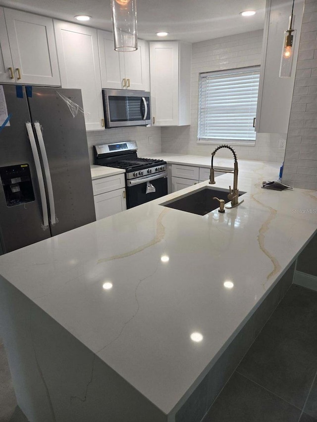 kitchen featuring white cabinets, stainless steel appliances, sink, and pendant lighting