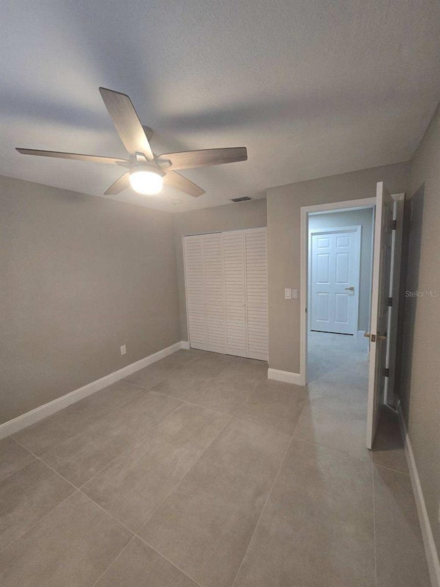 unfurnished bedroom with a textured ceiling, a closet, and ceiling fan