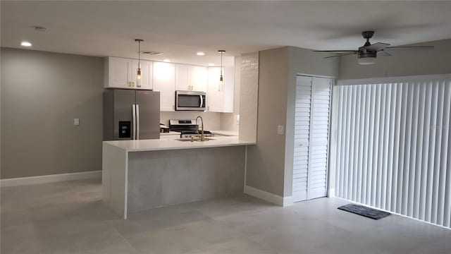 kitchen featuring pendant lighting, sink, appliances with stainless steel finishes, white cabinetry, and kitchen peninsula