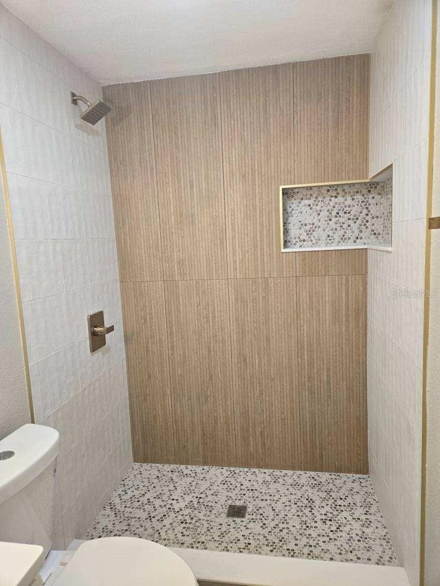 bathroom with toilet and tiled shower