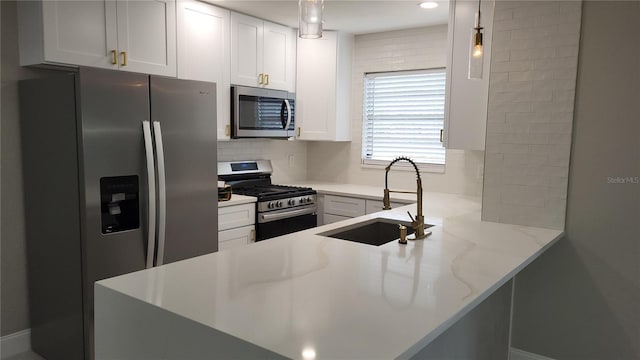 kitchen featuring sink, white cabinets, kitchen peninsula, stainless steel appliances, and light stone countertops