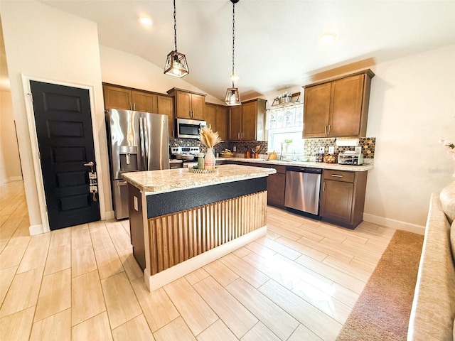 kitchen featuring appliances with stainless steel finishes, light wood-type flooring, a kitchen island, hanging light fixtures, and lofted ceiling