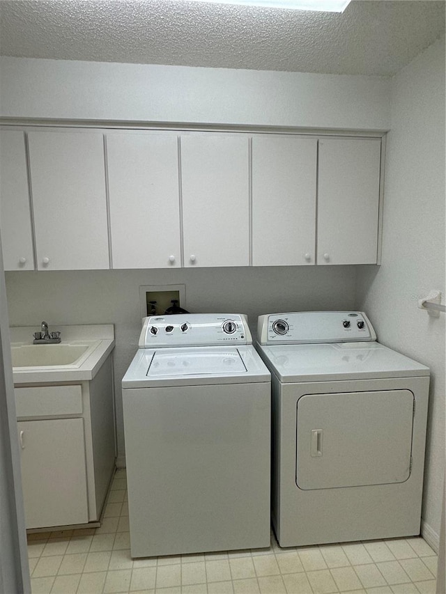 laundry area with sink, washer and dryer, a textured ceiling, and cabinets