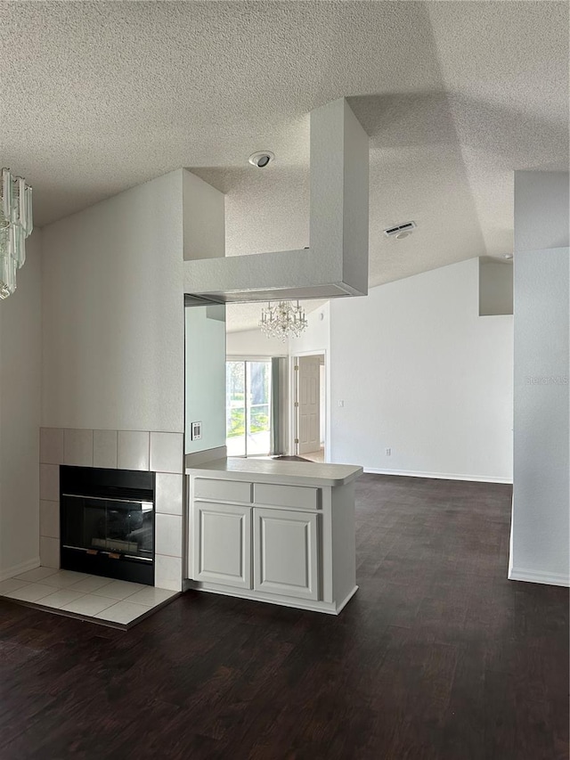 unfurnished living room with lofted ceiling, a textured ceiling, and dark hardwood / wood-style flooring