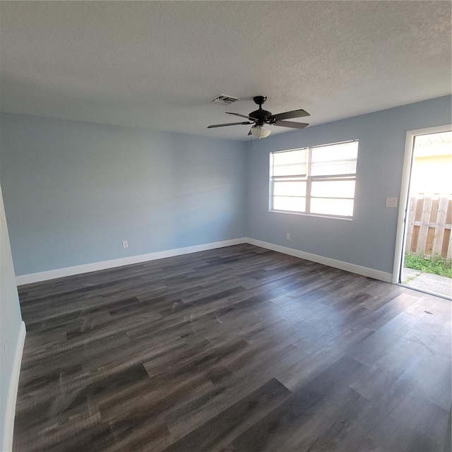 spare room featuring a textured ceiling, a healthy amount of sunlight, dark wood-type flooring, and ceiling fan