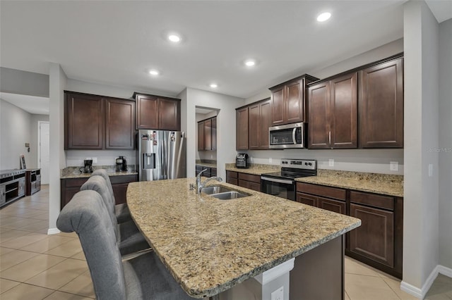 kitchen featuring sink, a breakfast bar area, light tile patterned floors, an island with sink, and stainless steel appliances