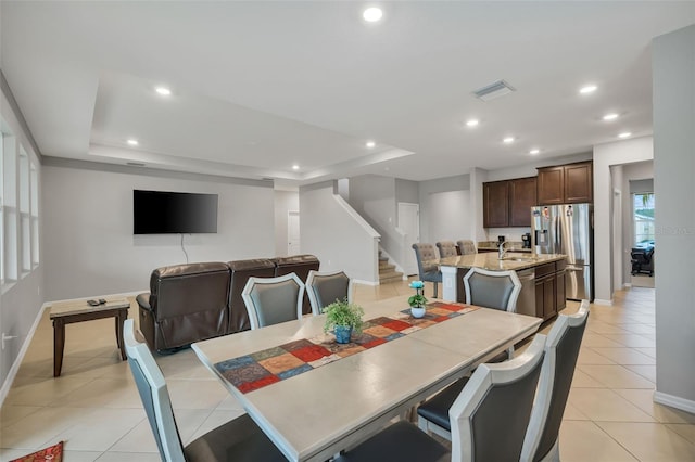 dining space featuring a raised ceiling, light tile patterned floors, and sink