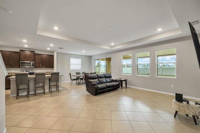 living room with light tile patterned floors and a tray ceiling