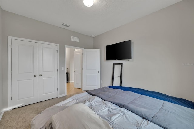 bedroom featuring light carpet, a closet, and a textured ceiling