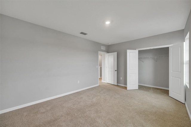 unfurnished bedroom featuring light carpet and a closet