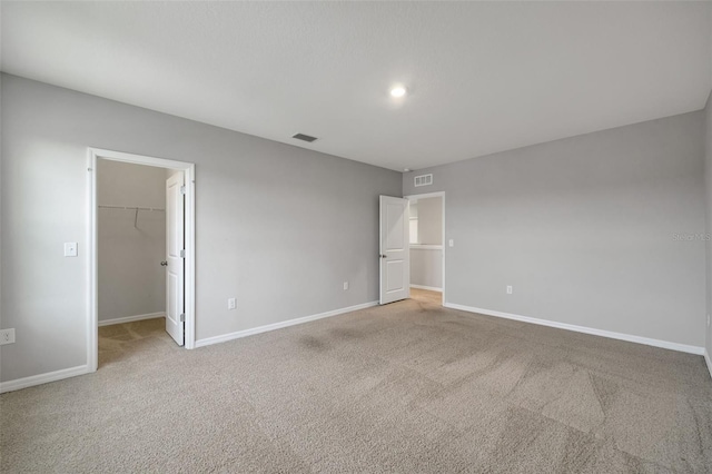 unfurnished bedroom with light colored carpet, a spacious closet, and a closet