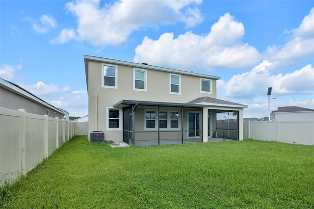 rear view of property with a lawn, central AC, and a sunroom