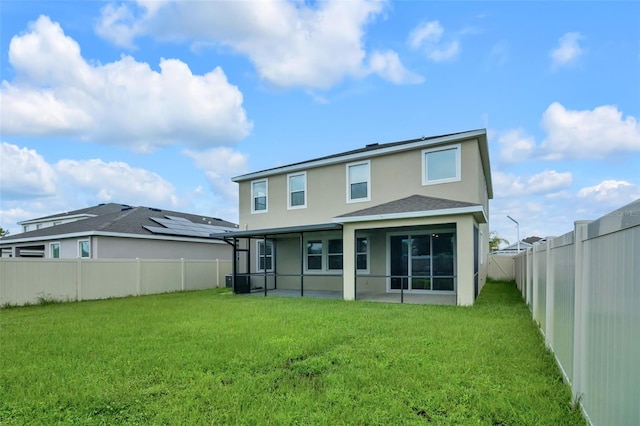 rear view of house with a sunroom, a patio area, and a yard