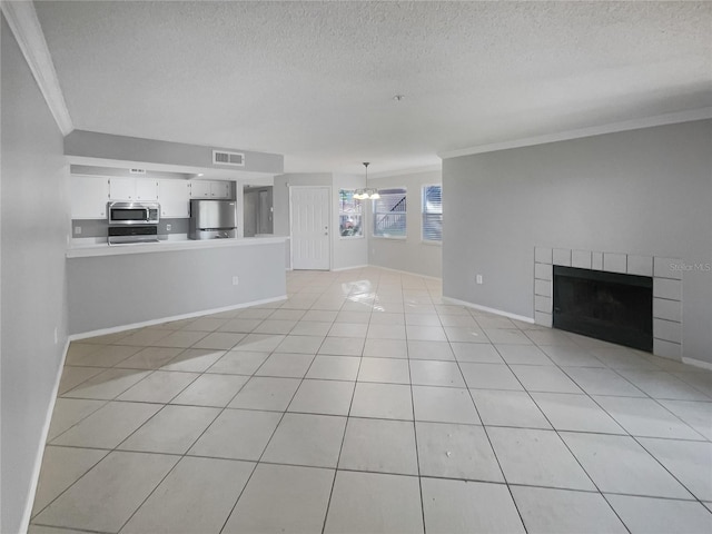 unfurnished living room featuring crown molding, a textured ceiling, a tile fireplace, and light tile patterned floors