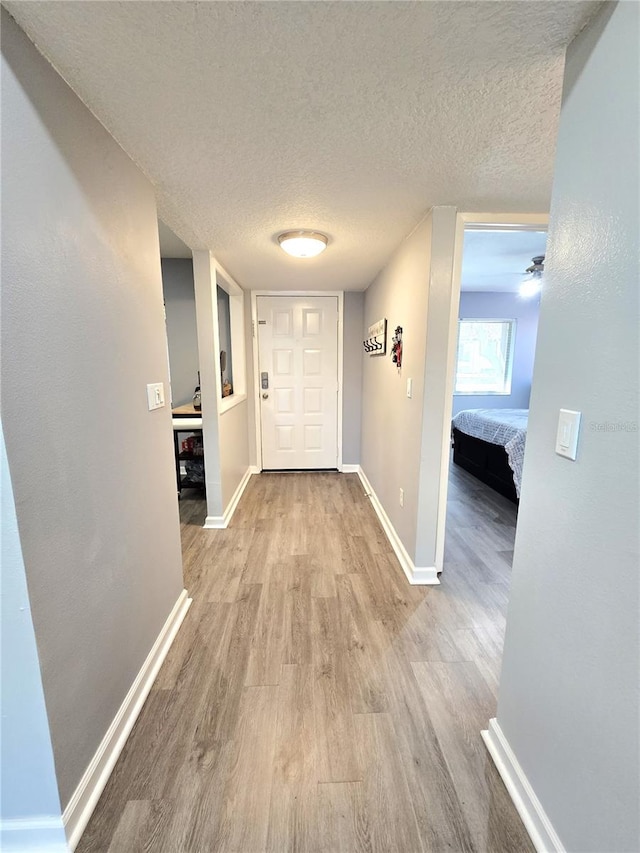 hallway featuring a textured ceiling and light hardwood / wood-style floors