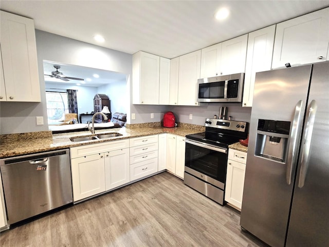 kitchen with white cabinets, appliances with stainless steel finishes, sink, and light stone counters