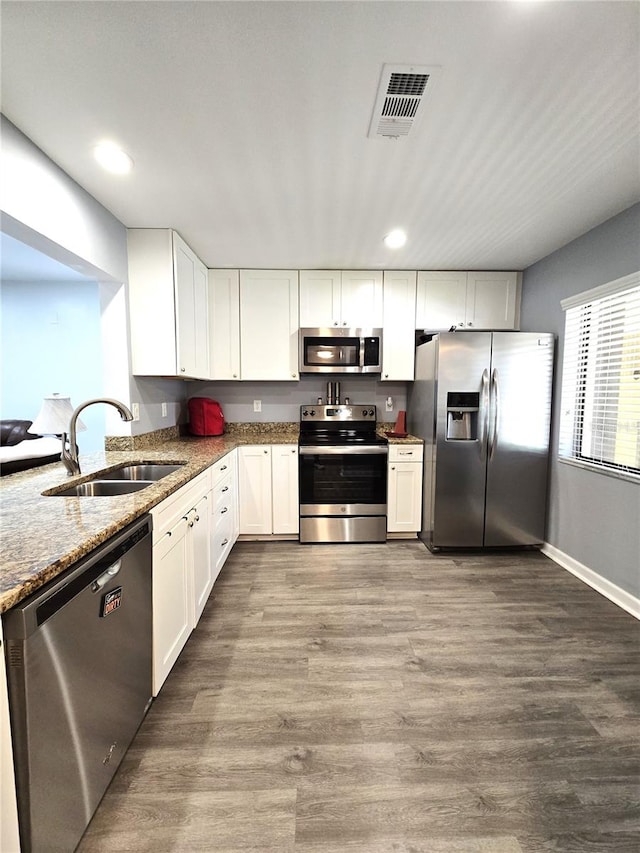 kitchen with white cabinetry, stainless steel appliances, dark hardwood / wood-style flooring, light stone countertops, and sink