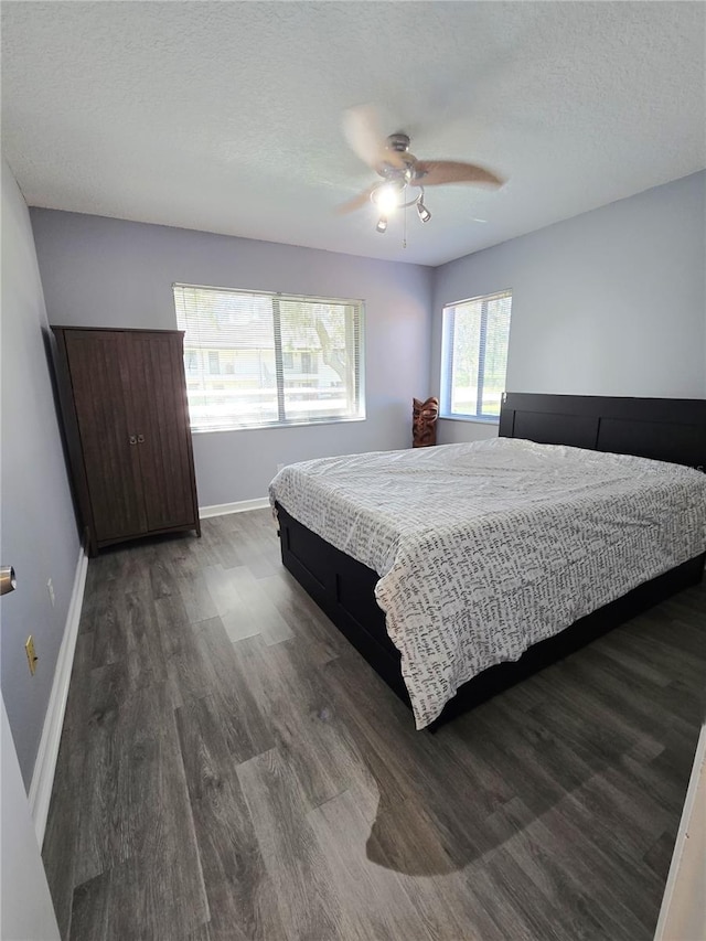 bedroom with ceiling fan, dark hardwood / wood-style floors, and a textured ceiling