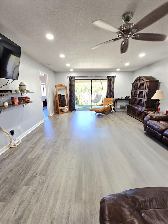 living room featuring a textured ceiling, ceiling fan, and wood-type flooring