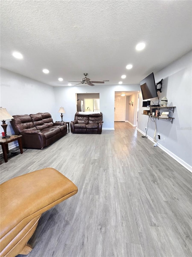 living room with ceiling fan, a textured ceiling, and hardwood / wood-style floors