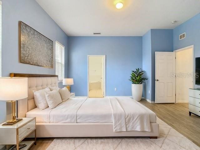 bedroom featuring ensuite bathroom and light hardwood / wood-style floors