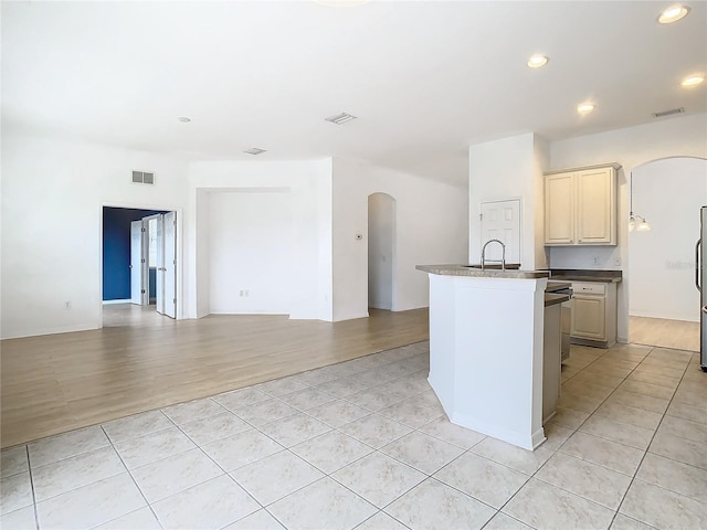 kitchen with sink, cream cabinets, light tile patterned floors, and stainless steel refrigerator