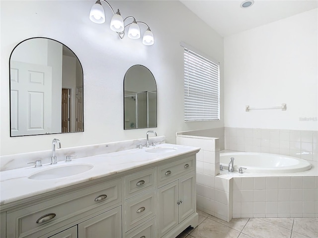 bathroom with tiled tub, vanity, and tile patterned flooring