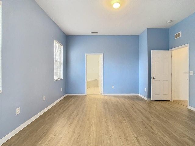 unfurnished bedroom featuring light hardwood / wood-style flooring and connected bathroom