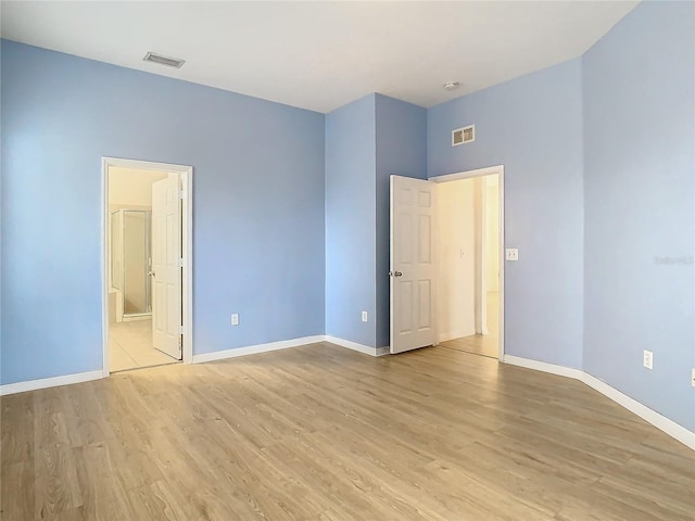 unfurnished bedroom featuring light wood-type flooring and connected bathroom