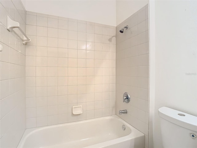 bathroom with tiled shower / bath combo and toilet