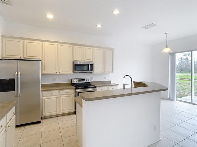 kitchen featuring light tile patterned floors, hanging light fixtures, appliances with stainless steel finishes, and a kitchen island with sink